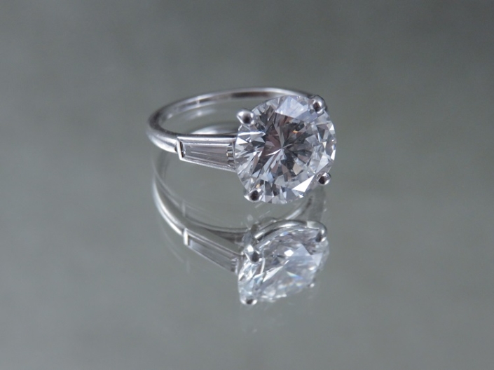 CARTIER, Paris. Bague en platine, ornée d'un diamant brillant d'environ 3,93 ct, épaulé de deux baguettes. Adjugée 83 750 €